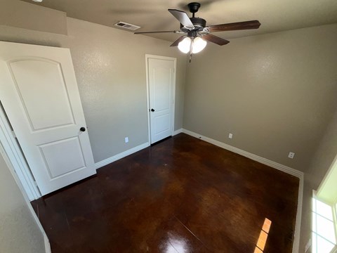 A room with a ceiling fan and wood flooring.