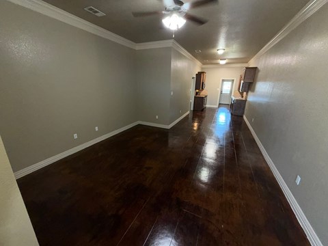 A long hallway with wood floors and a ceiling fan.