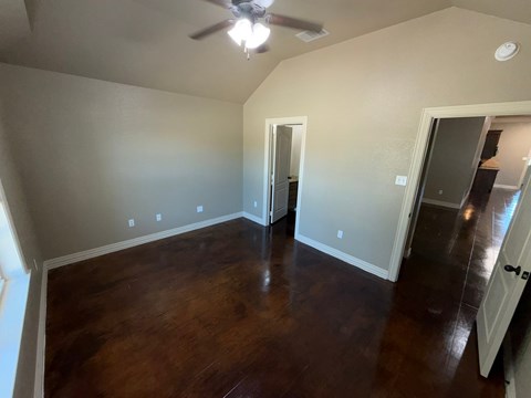 A room with a ceiling fan and wooden floors.