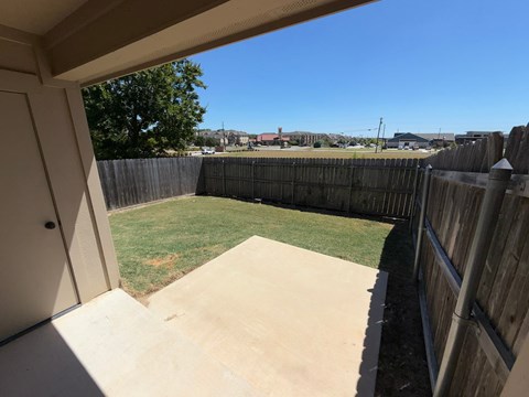 A backyard with a concrete patio and a wooden fence.