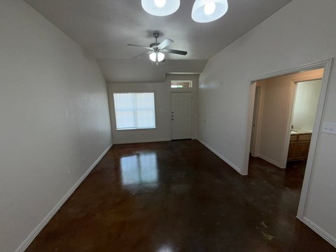 A room with a brown floor and a ceiling fan.