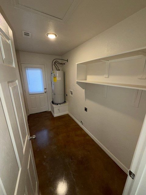A white room with a water heater and a window.