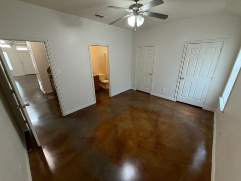 A room with a brown floor and a ceiling fan.