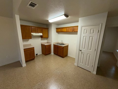 A kitchen area with a sink, cabinets, and a door.
