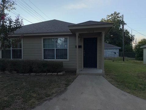 A small house with a brown roof and a black door.
