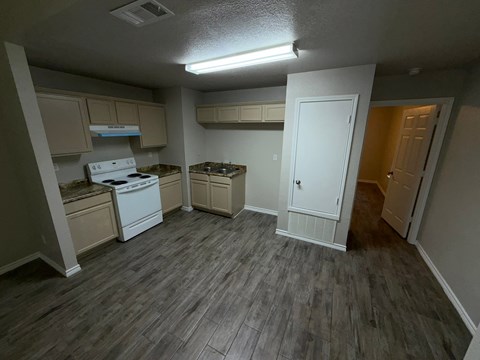 A kitchen with a white stove top oven and a white door.