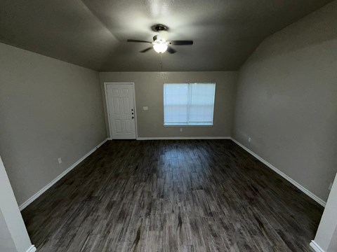 A room with a ceiling fan and wooden flooring.