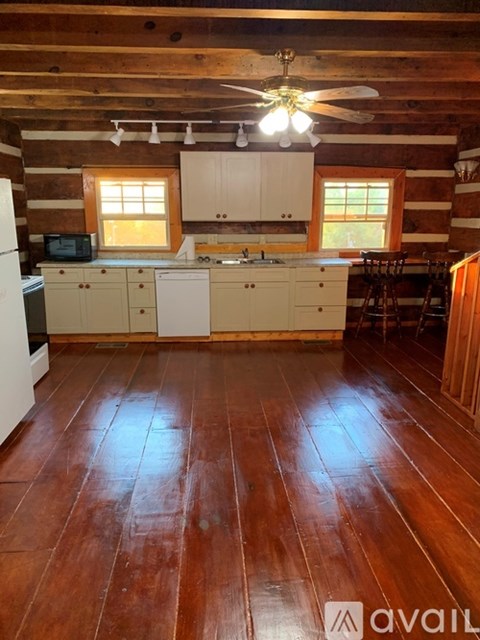 A kitchen with wooden floors and a ceiling fan.