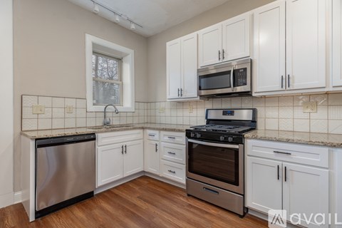 A kitchen with white cabinets and a black stove top oven.