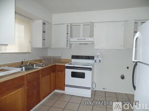 A kitchen with a white refrigerator, white oven, and wooden cabinets.