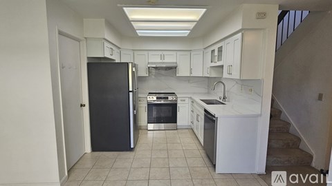A kitchen with white cabinets and a black refrigerator.