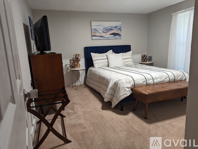 A bedroom with a bed, a television, and a chair.