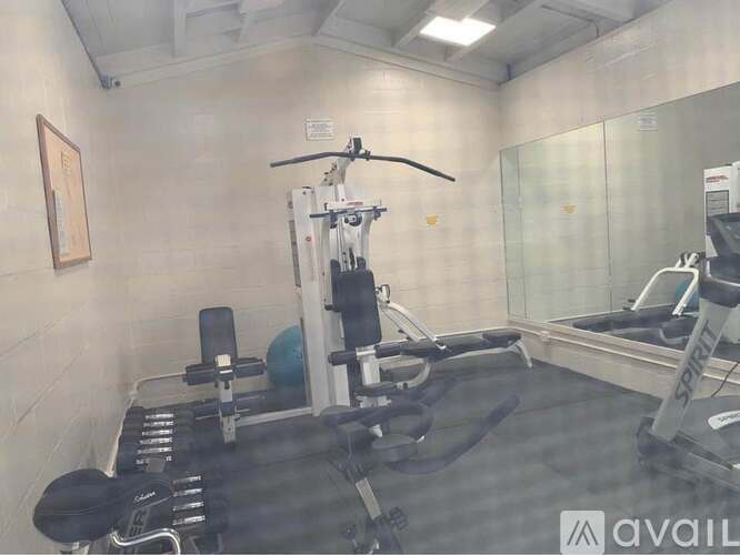 A gym with a weight bench, a barbell and a mirror.