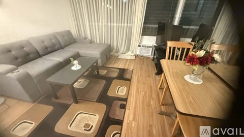 A living room with a grey sofa, wooden coffee table, and a wooden dining table with chairs.