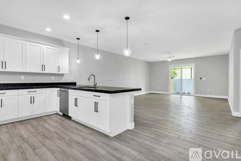 A modern kitchen with white cabinets and a black countertop.