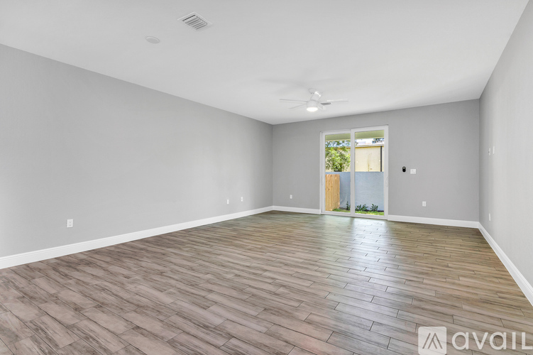 A spacious room with wooden flooring and a ceiling fan.