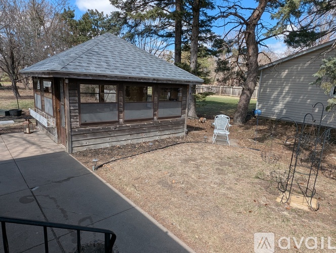 A gazebo is situated in a backyard with a lawn and a fence.