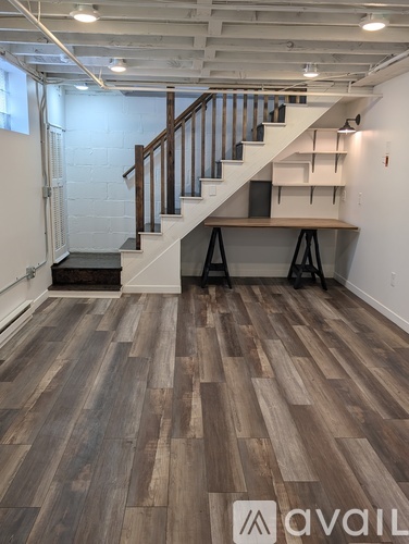 A room with wooden flooring and a staircase with a wooden handrail.