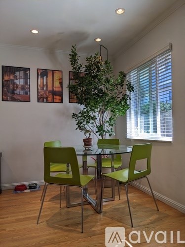 A dining room with a glass table and green chairs.