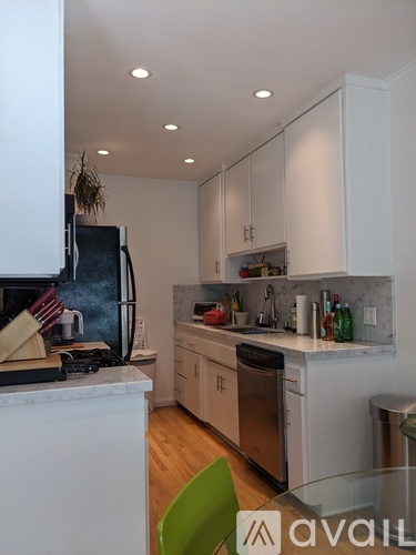 A kitchen with white cabinets and a green chair.