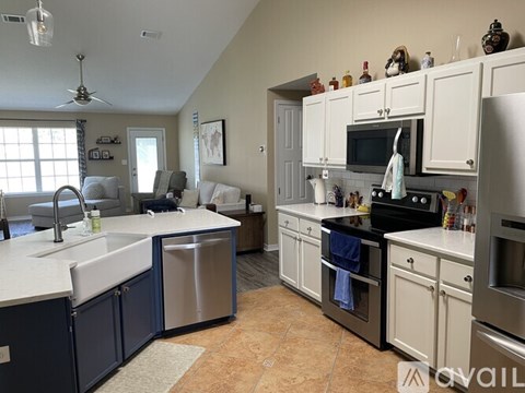 A kitchen with white cabinets and a blue island.