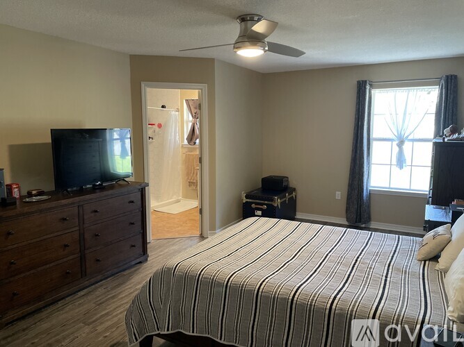 A bedroom with a bed, dresser, and television.