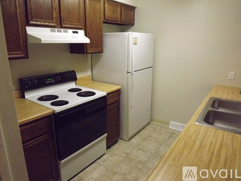 A kitchen with a stove, refrigerator, and sink.