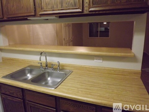 A kitchen counter with a sink and wooden cabinets.