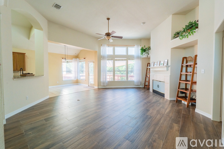 A spacious living room with wood flooring and a ceiling fan.