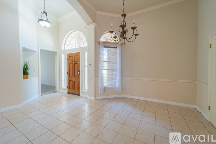 A spacious room with a chandelier and a door leading to another room.