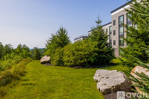 A modern building is surrounded by a well-manicured lawn and trees.