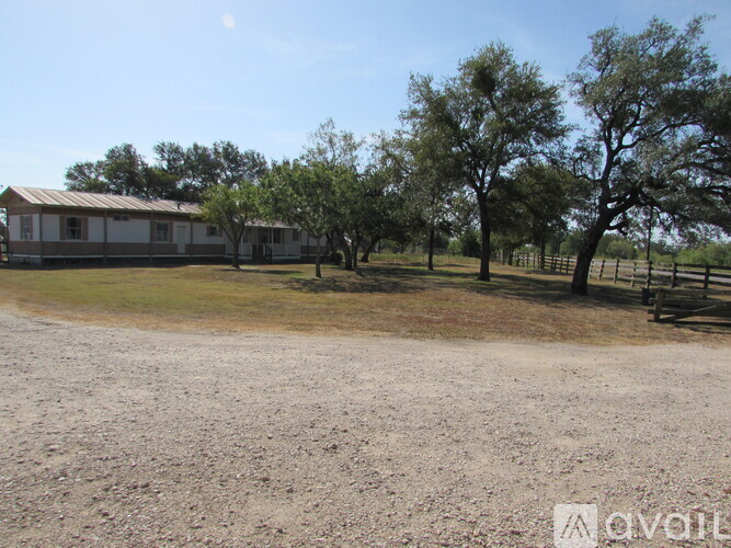 A house is surrounded by trees and a dirt road.