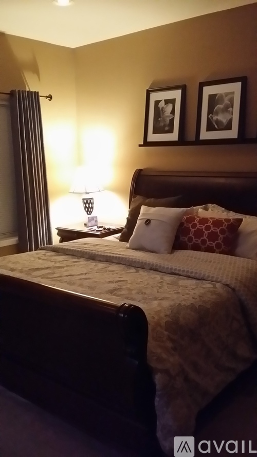 A bedroom with a bed, pillows, and a lamp.