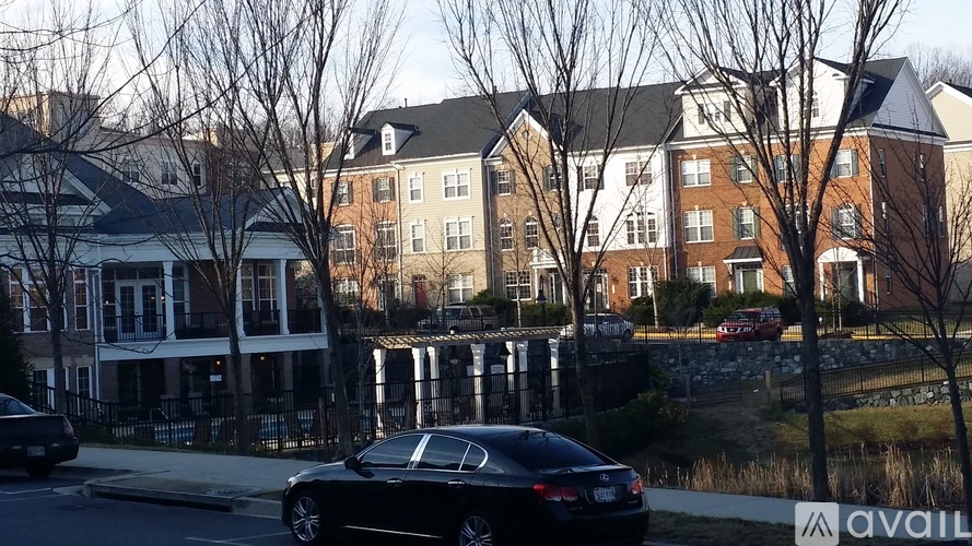 A black car is parked on the side of a street in front of a building.