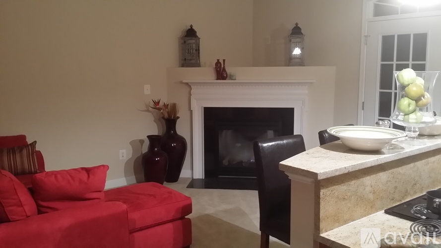 A living room with a red couch, a fireplace, and a dining table set for two.