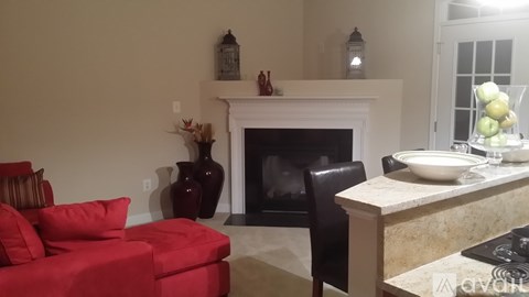 A living room with a red couch, a fireplace, and a dining table set for two.