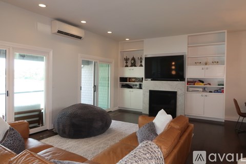 A living room with a brown leather couch and a white rug.