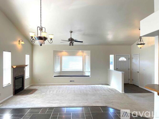 A spacious living room with a fireplace and a ceiling fan.