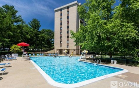 A large swimming pool with a red umbrella and a tall building in the background.