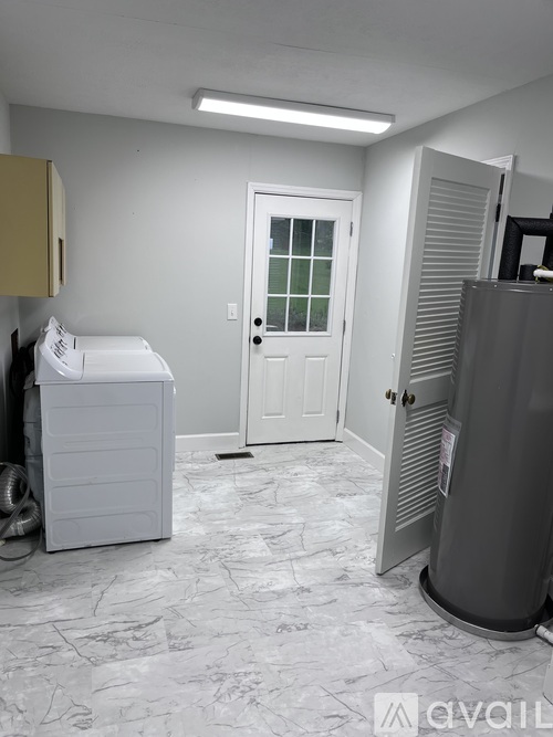 A white washing machine sits in a room with a door and a window.