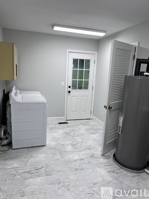 A white washing machine sits in a room with a door and a window.