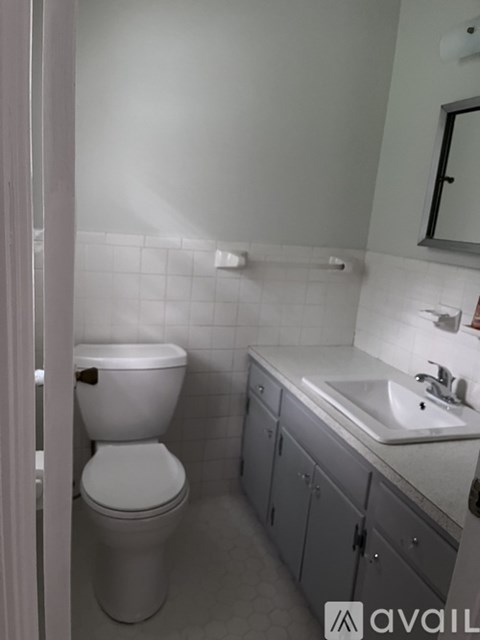 A white toilet is in a bathroom with a sink and mirror.