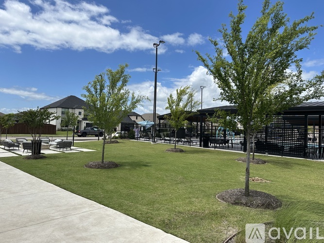 A park with grass and trees in the foreground and a building in the background.