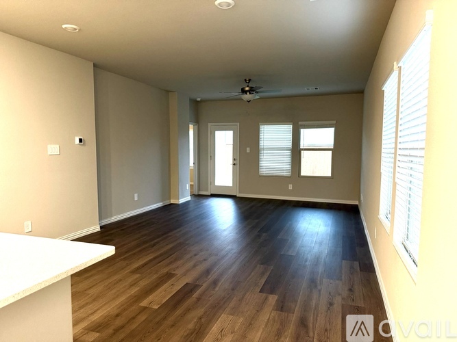 A spacious room with wooden floors and a ceiling fan.