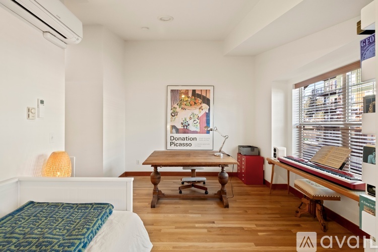 A bedroom with a bed, desk, and a poster of a painting.