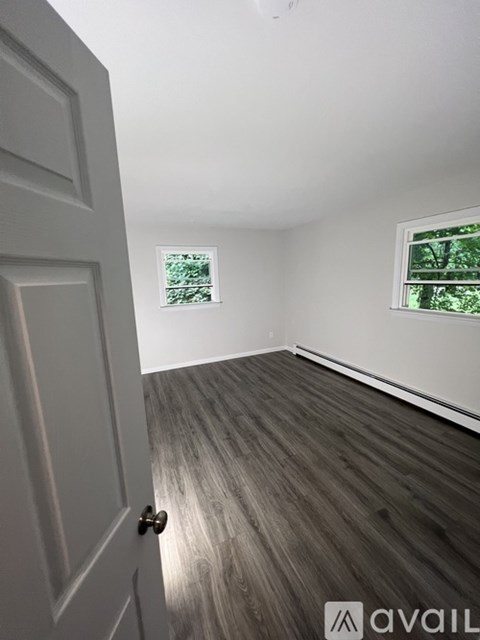 A room with a white door and a window with a view of trees.