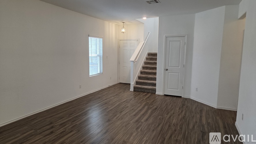A room with wooden floors and a staircase leading to another room.