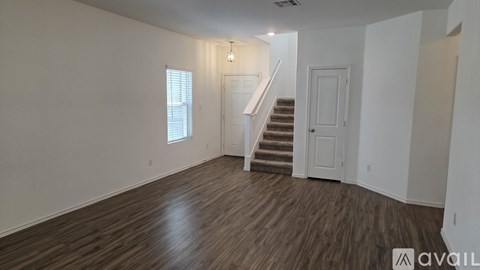 A room with wooden floors and a staircase leading to another room.