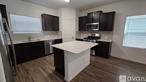 A kitchen with black cabinets and a white island.