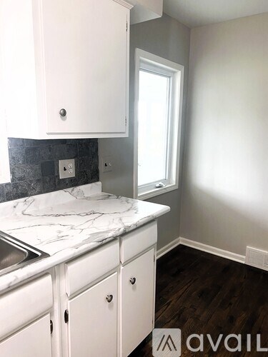 A kitchen with white cabinets and a marble countertop.